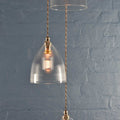 Margate Small Ribbed glass pendant light with ribbed shade and vintage-style bulb hanging against blue brick wall