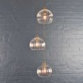Soho medium ribbed glass 3-cluster pendant light with hand-blown globes and vintage filament bulbs against a gray brick wall