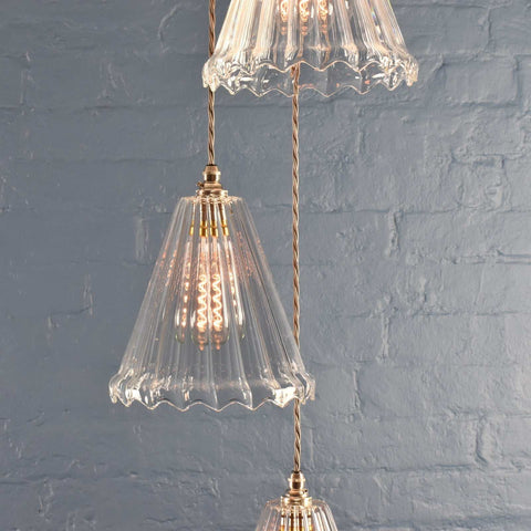 Rye medium ribbed glass shade cluster pendant light with hand-blown glass and adjustable cords against a gray brick wall background