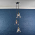 Rye medium ribbed glass shade cluster pendant light with three hand-blown glass shades and adjustable cords against blue brick wall