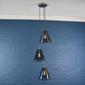 Rye medium smoked glass shade cluster pendant light with three hand-blown smoked glass shades hanging on adjustable cords against a blue wall background