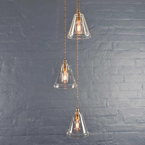 Rye small clear glass shade cluster pendant light with hand-blown glass and adjustable hanging lengths against a gray brick wall