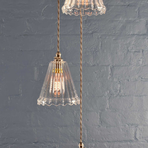 Rye small ribbed glass shade cluster pendant light with hand-blown glass and adjustable flex cables against a gray brick wall background