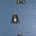 Rye small smoked glass shade cluster pendant light with hand-blown glass shades and adjustable flex against a blue brick wall background