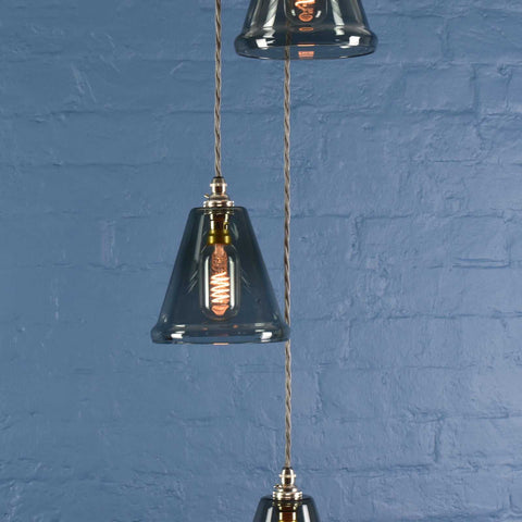 Rye small smoked glass shade cluster pendant light with hand-blown glass shades and adjustable flex against a blue brick wall background