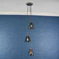 Rye small smoked glass shade cluster pendant light with three hand-blown glass shades hanging against a blue brick wall